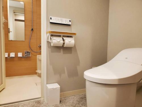 广岛Trust Hotel的浴室设有白色的卫生间和镜子