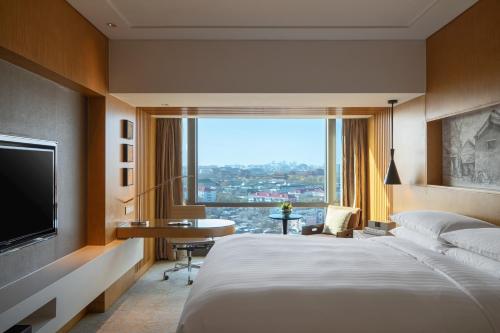 北京北京金茂万丽酒店的酒店客房配有一张床、一张书桌和一台电视。