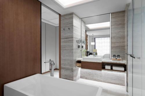 南汇上海中优城市万豪酒店的一间带浴缸和大镜子的浴室