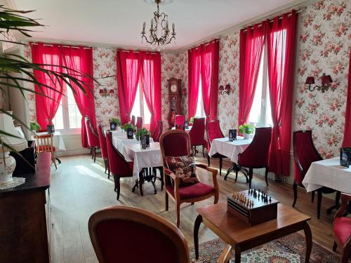 勒阿弗尔Hotel de Charme La Bonne Adresse的餐厅设有红色窗帘和桌椅