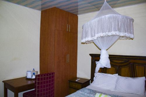 利隆圭Demera Motel的一间卧室配有一张床和一张书桌,另一张床配有窗帘