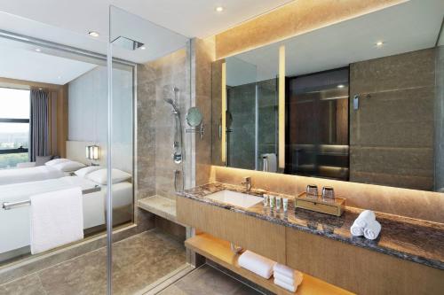 郑州郑州航空港万怡酒店的一间带水槽和淋浴的浴室以及一张床