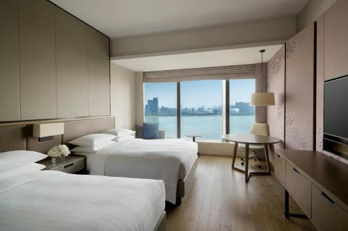杭州杭州钱江新城万豪酒店的酒店客房设有两张床、一张桌子和一个窗户。