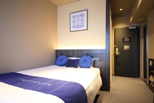 大阪Dynasty Hotel & Resort Osaka的一间卧室配有一张带蓝色枕头的大床