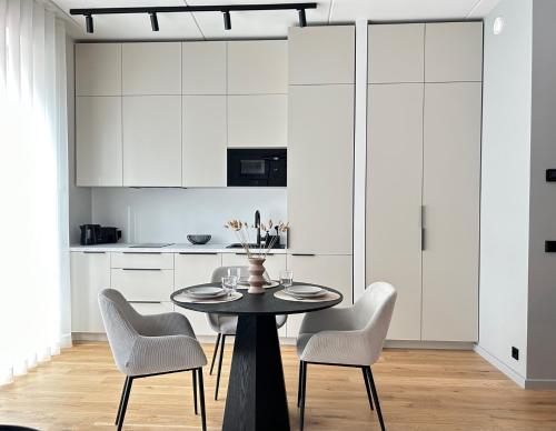 派尔努Esplanaadi Residences的厨房配有白色橱柜和桌椅