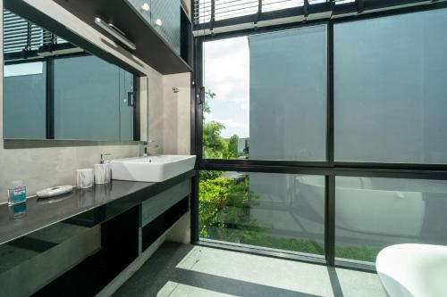 普吉镇Villa Lami - Tropical Modern Loft Phuket with 3BD, private pool, Gym and Sauna的一间带水槽和大窗户的浴室