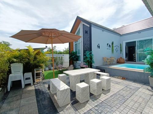 清刊Khiangkhoo Pool Villa ChiangKhan - เคียงคู่พูลวิลล่าเชียงคาน的庭院配有遮阳伞和桌椅。