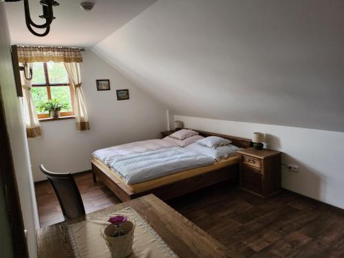 萨扎瓦Hospůdka Na Trucovně的一间卧室配有一张床、一张桌子和一个窗户。