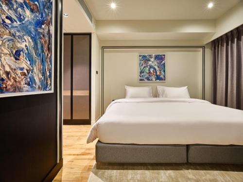曼谷Floral Court Hotel & Residence Sukhumvit 13的一间卧室配有一张大床和一幅画
