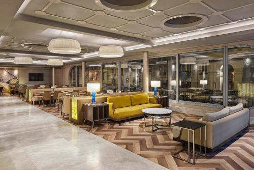 柏林TITANIC Comfort Mitte的酒店大堂设有黄色的沙发和桌子