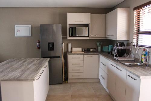 比勒陀利亚Annexure A - Lovely brand new 2 bedroom flat in Groenkloof的厨房配有白色橱柜和不锈钢冰箱