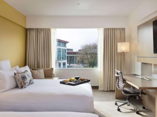 奥克兰奥克兰艾勒斯利诺富特酒店的配有一张床和一张书桌的酒店客房