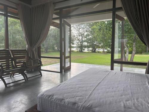 NikaweratiyaMagalle Wewa Villa的一间卧室设有床铺和大型玻璃窗