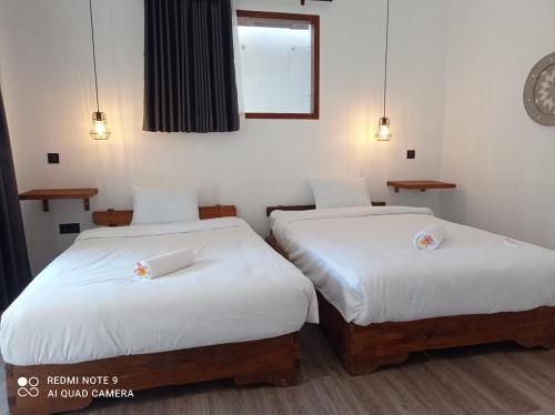 龙目岛库塔Sekar Kuning Bungalows的配有白色床单的客房内的两张床