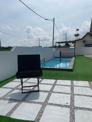Kampong Bukit KatilTraditional Melaka Homestay with Private Pool的椅子坐在带游泳池的庭院