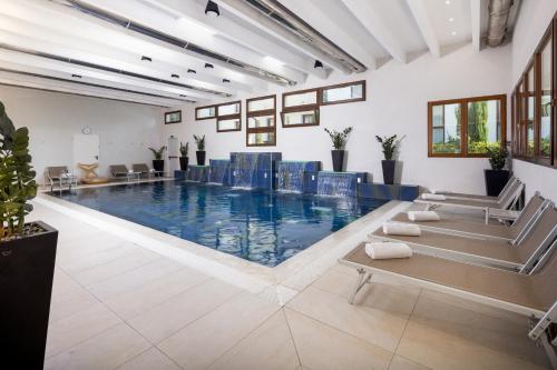 坎波加利亚诺贝斯特韦斯特摩德纳区酒店的大楼内带蓝色椅子的大型游泳池