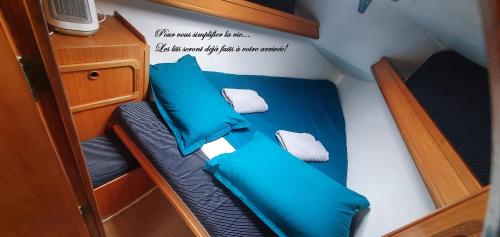 拉罗谢尔Nuits au Port - vieux port - "Super Castor" voilier à quai的小船中的一张小床,上面有蓝色的枕头