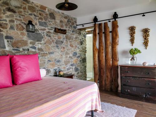 阿科达卡列塔Calhau Grande的一间卧室设有一张床和石墙