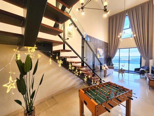 新山Loft Suite Seaview JB CIQ 7Pax的客厅设有玻璃桌上足球和楼梯