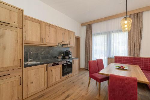 巴德哥依斯恩Appartementhaus Dachsteinblick mit Indoorpool und Sauna的厨房配有木制橱柜和一张带红色椅子的桌子。