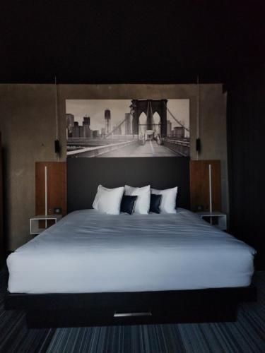 拉瓦尔Grand Times Hotel Laval - Centropolis的一间卧室配有一张大床,并画着一座桥