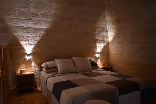 卡诺萨迪普利亚Faliero Room的卧室配有砖墙内的床铺