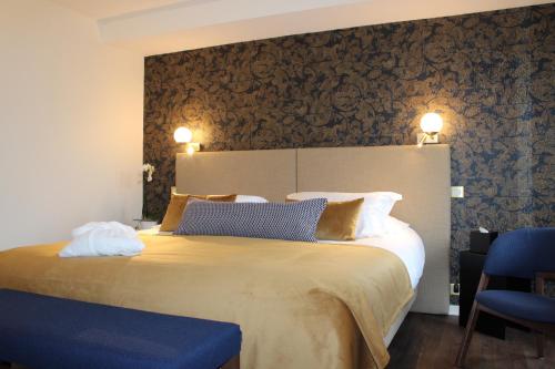 布里夫拉盖亚尔德Hôtel La Truffe Noire的一间卧室配有一张大床和一张蓝色椅子