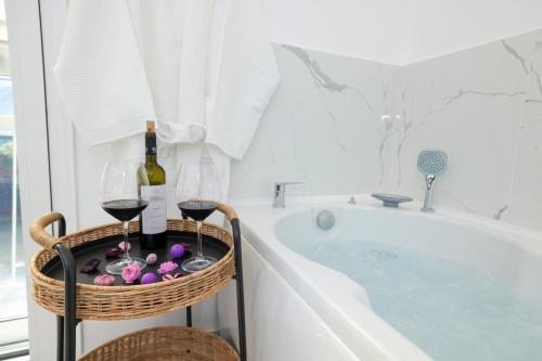 雅典3bd jacuzzi mansion的浴缸配有两杯葡萄酒和一篮酒杯