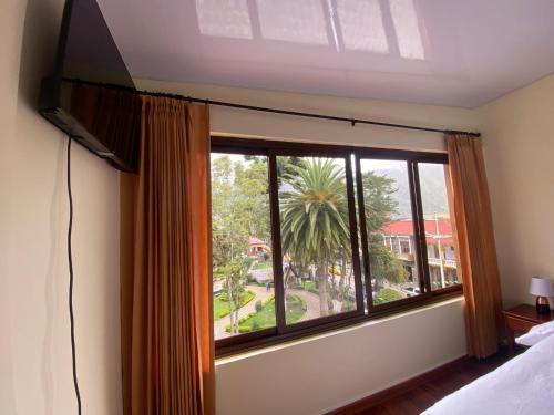 巴尼奥斯Hostal Magdala的一间卧室设有窗户,享有棕榈树的景色