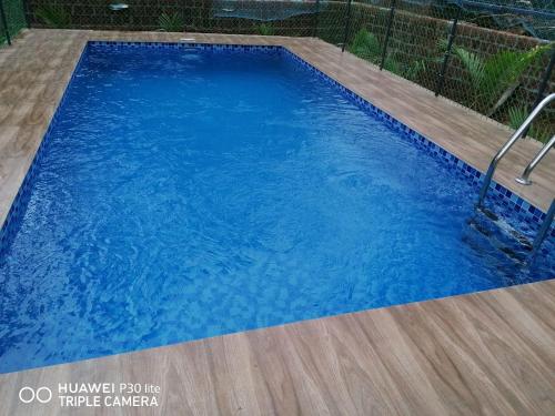 坎努尔Thekkumbath Sea Breeze Pool villa的铺有木地板的大型蓝色游泳池