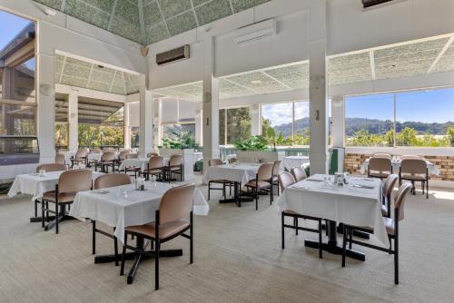 科夫斯港星座酒店汽车旅馆的餐厅设有白色的桌椅和大窗户。