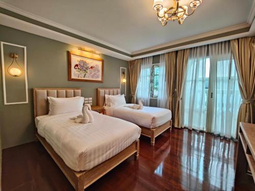 曼谷Siri Grand Bangkok Hotel的酒店客房设有两张床和吊灯。
