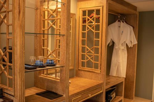 曼谷Siri Grand Bangkok Hotel的衣柜里装有白色衬衫的木柜