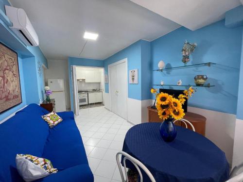 墨西拿La casa di Dafne的蓝色的客房配有蓝色的沙发和带鲜花的桌子