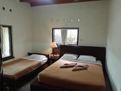 姆杜克古鲁拉特纳民宿的客房设有两张床、一盏灯和两扇窗户。