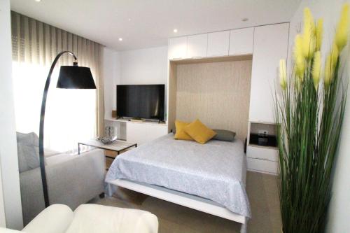 圣地亚哥德拉里贝拉Elvira Home Santiago de la Ribera Beach 24c, Mar Menor的一间卧室配有一张带黄色枕头的床和一台电视。