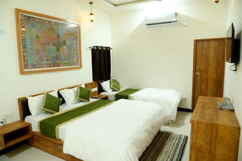 斋沙默尔The Travel Bug Jaisalmer的一间卧室设有两张床,墙上挂着一幅画