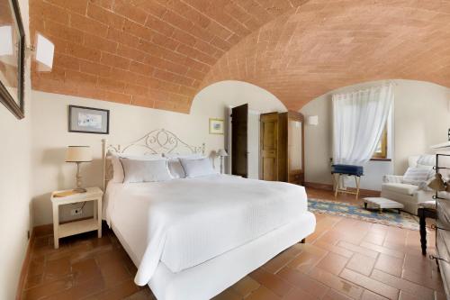 贝托勒Villa Vignacce - Boutique Country Resort的卧室配有一张白色大床和一把椅子