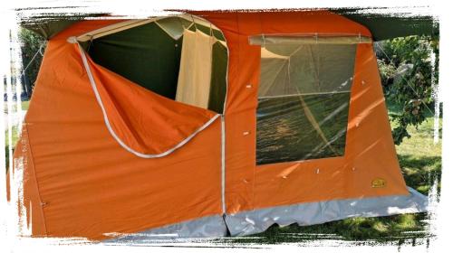 德兰斯克DDR Kult Steilwandzelt POUCH direkt am Strand的橙色的帐篷坐在草地上