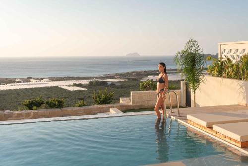 法拉萨纳Falasarna Luxury Villas的站在游泳池旁的比基尼的女人