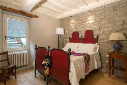 菲耶索莱Casa Sofia的一间石墙卧室,配有红色的床