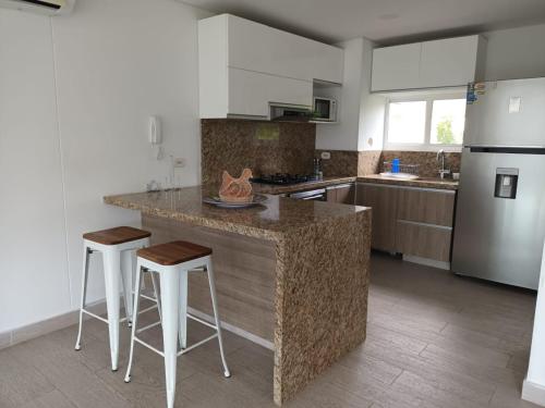 圣玛尔塔Beautiful Beach Apartment in Zazue的厨房配有带凳子的柜台和冰箱。