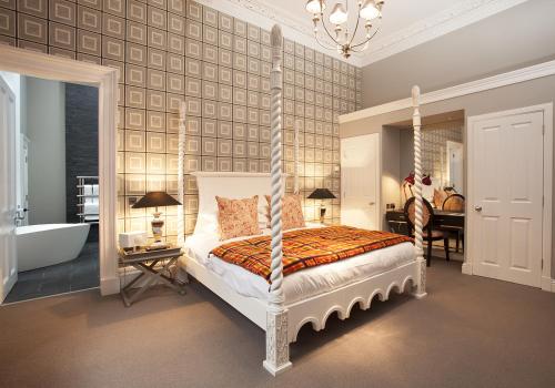 爱丁堡The Rutland Hotel & Apartments的一间卧室配有一张天蓬床和一个浴缸
