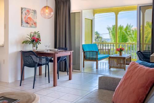 克拉伦代克Diver's Paradise Bonaire的一间带桌椅的客厅和一个阳台