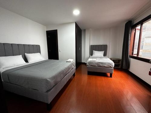 波哥大Hotel The MIRROR的一间卧室设有两张床和窗户。