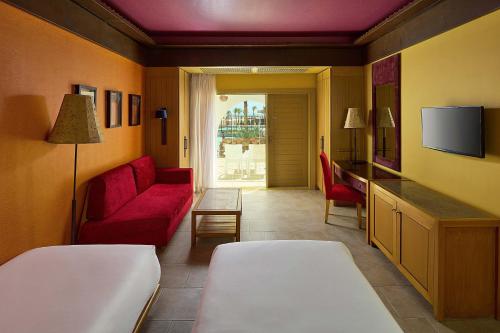 达哈布Retac Qunay Dahab Resort & SPA的酒店客房设有红色的沙发和电视。