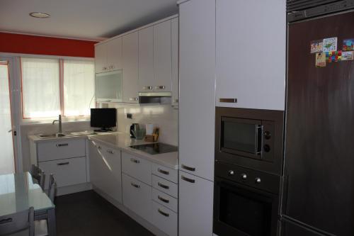 维戈Calle Areal muy céntrico的厨房配有白色橱柜和黑色用具