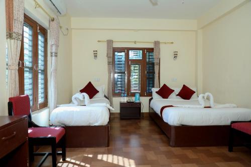 索拉哈Hotel Vista Chitwan的带3张红色和白色枕头的床的房间