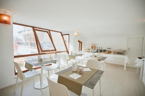 菲乌米奇诺Castrichella Boutique Hotel Rome Airport的一间设有白色桌子和白色椅子的餐厅