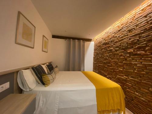 毕尔巴鄂Apartamento Deluxe Casco Viejo的一间卧室配有一张砖墙床